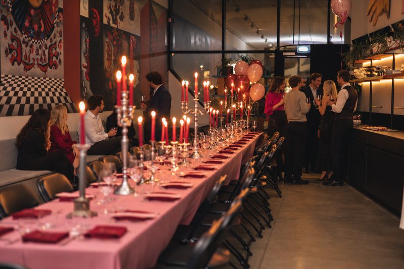 Ilgas stalas su žvakėmis ir svečiai MO Bistro.
